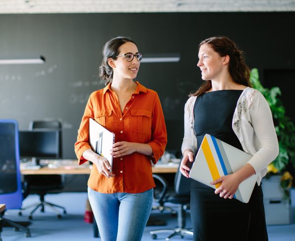 Two women walking in an office.